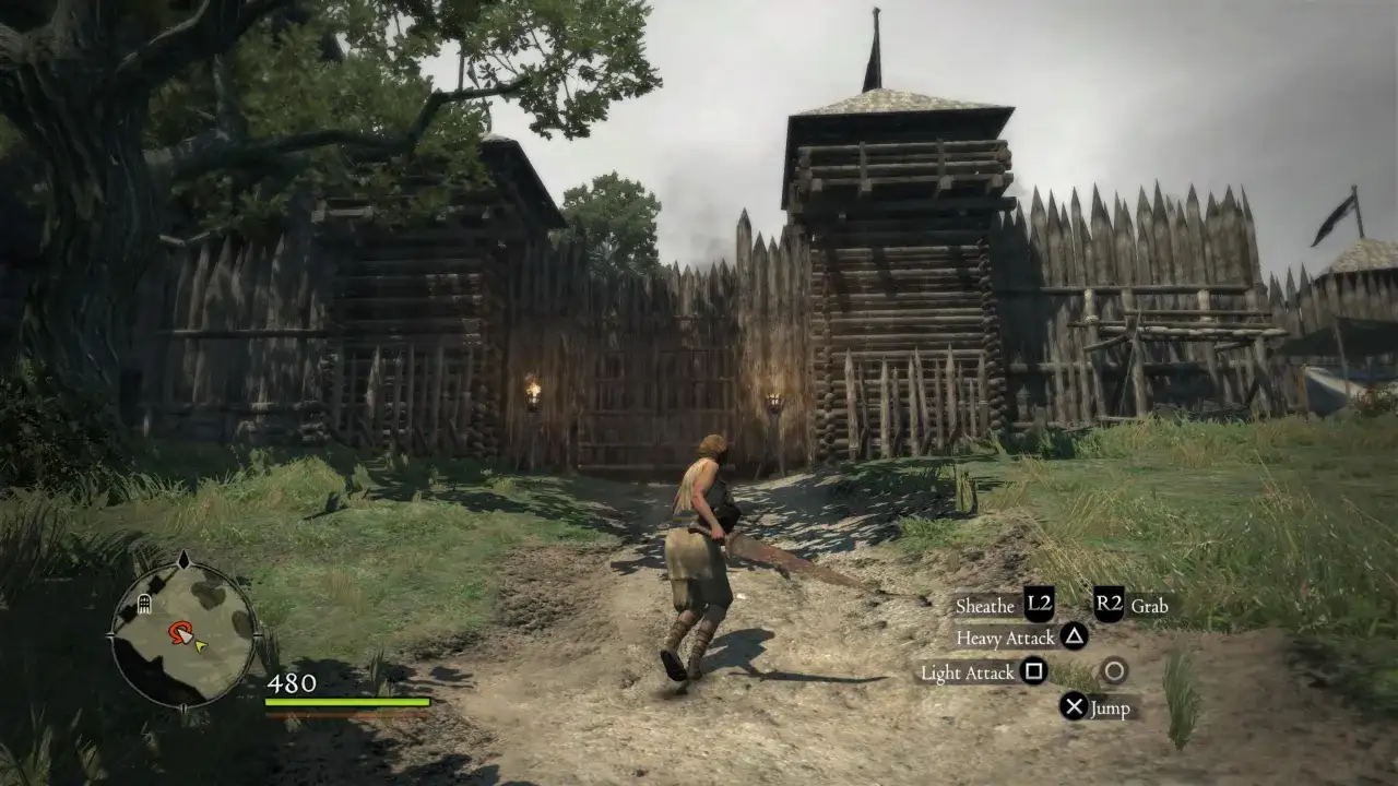 Postać w grze Dragon's Dogma 1 zbliża się do drewnianej bramy warownej.