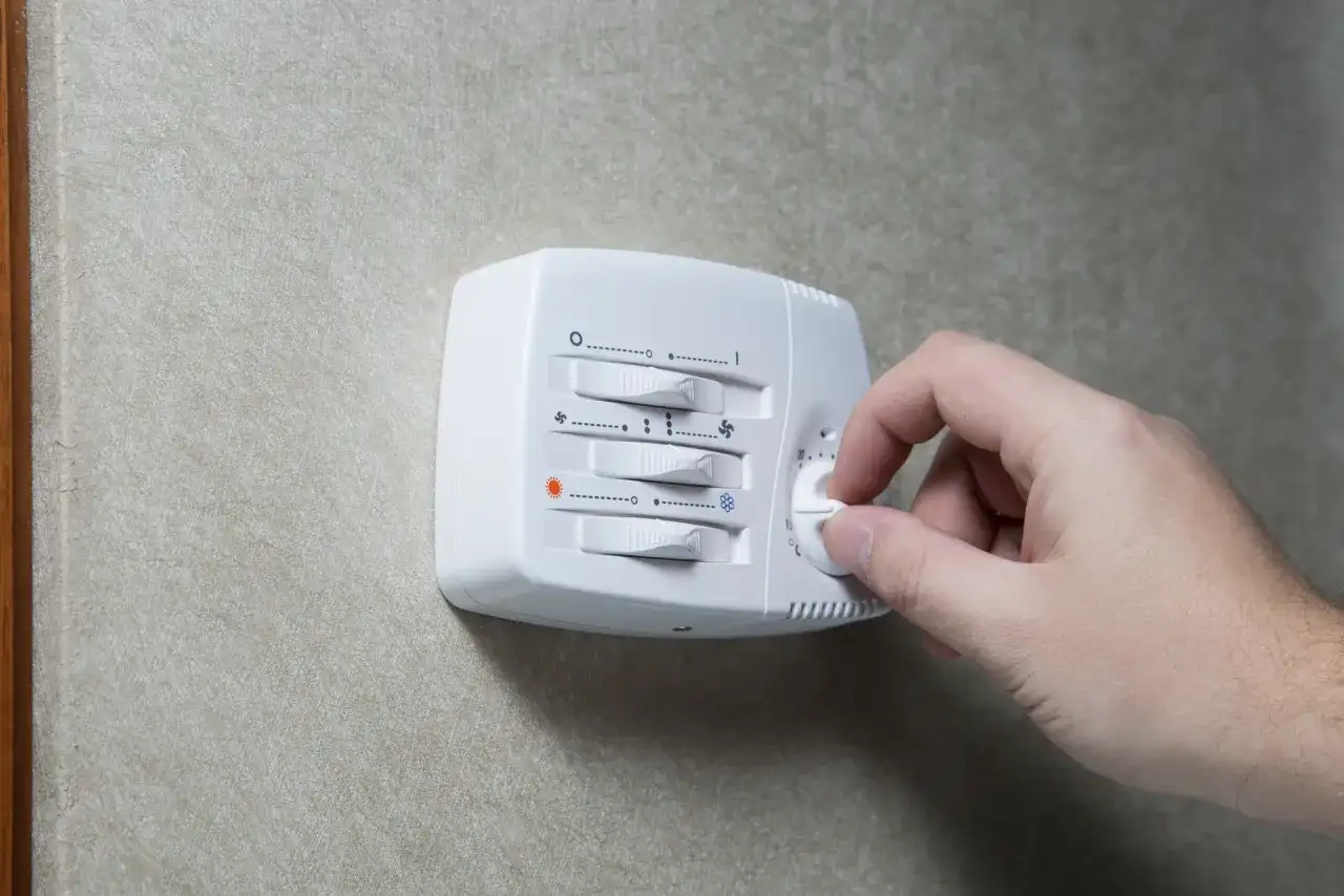 Dłoń kręci pokrętłem termostatu. Ustawienie temperatury wpływa na pracę kotła, a jego histereza decyduje o częstotliwości włączania i wyłączania.