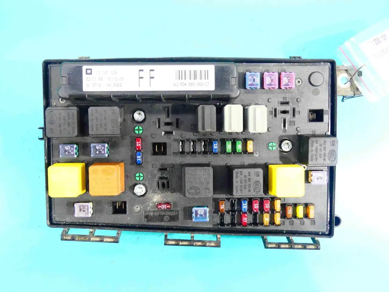 Panel bezpieczników do Opla Astry H z widocznymi bezpiecznikami i przekaźnikami.