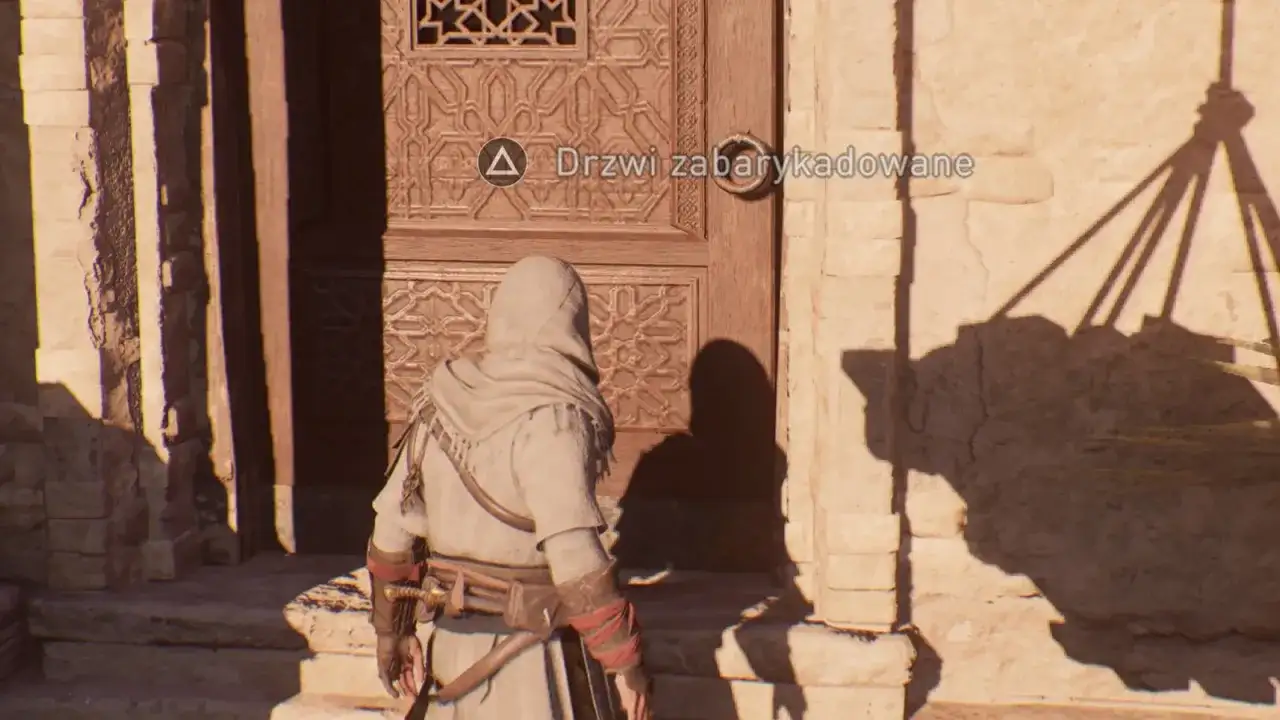 Postać w kapturze stoi przed drzwiami, na których widnieje napis "Drzwi zabarykadowane".