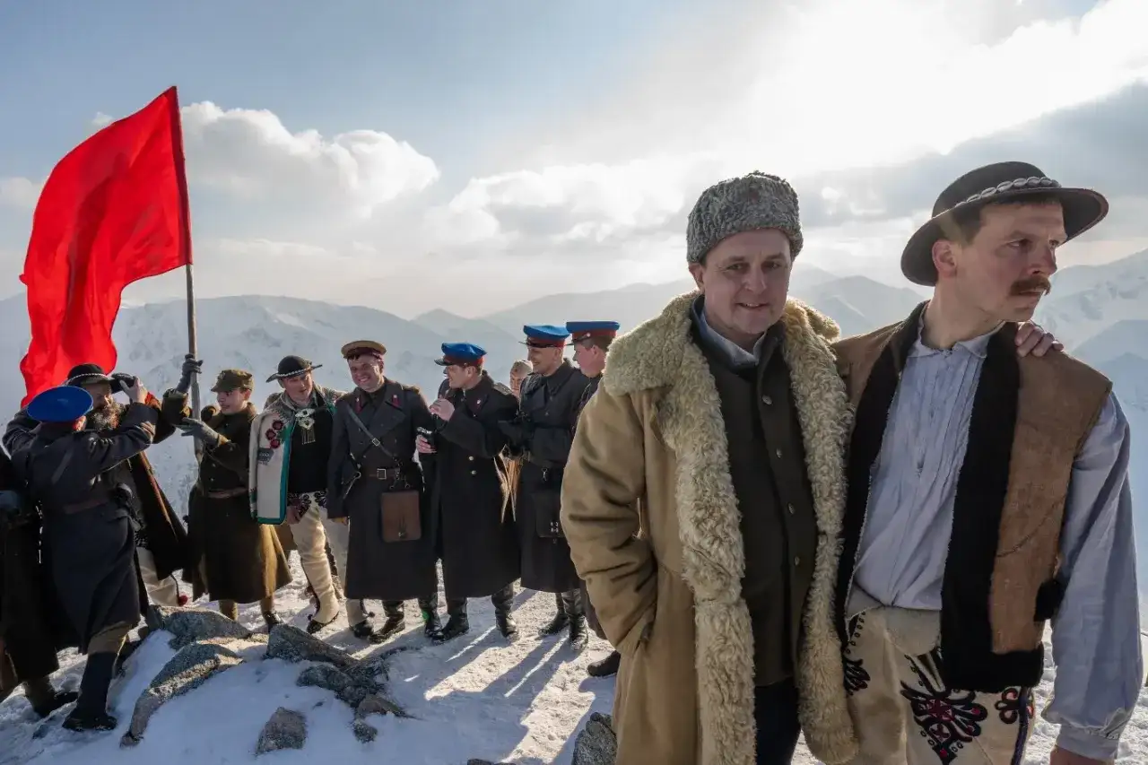 Grupa ludzi w strojach historycznych na tle gór. Czerwona flaga powiewa na wietrze. To może być scena z filmu, która zasługuje na biała odwaga recenzja.