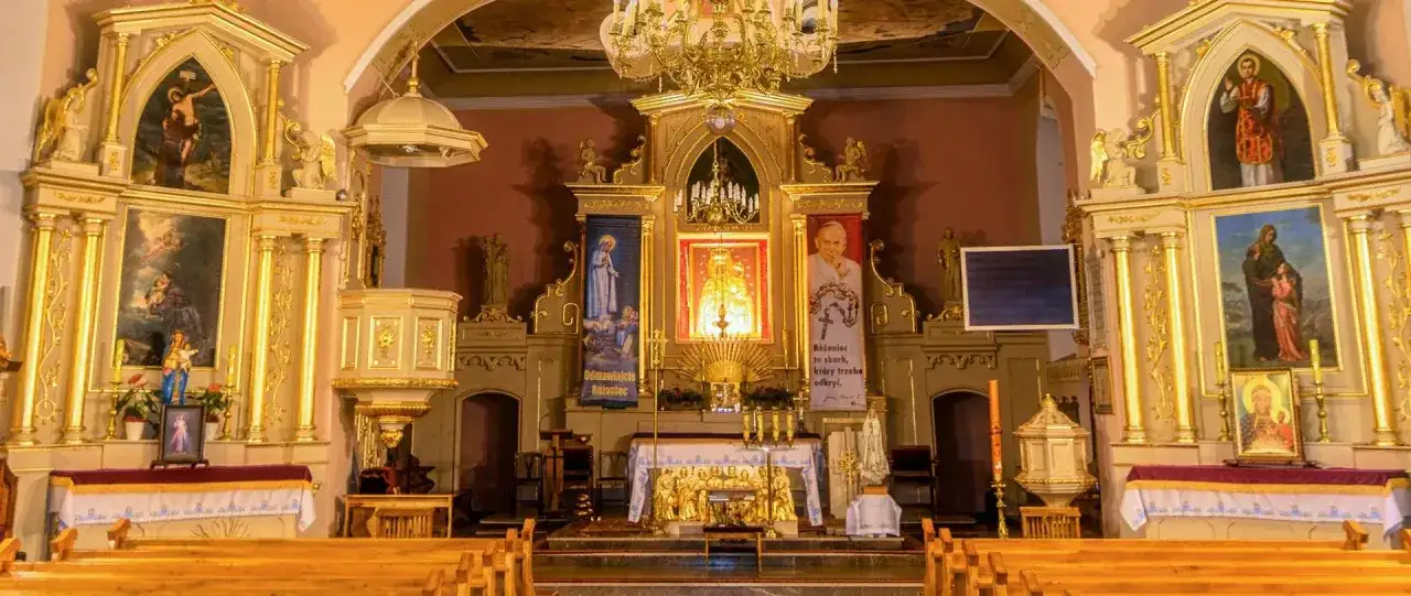 Ołtarz główny kościoła z obrazami świętych i portretem Jana Pawła II.