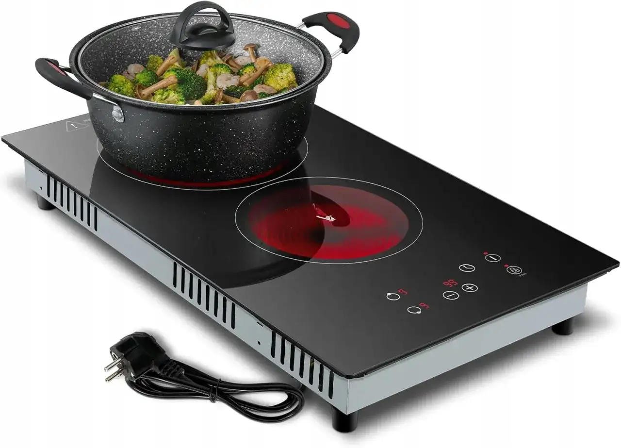 Płyta ceramiczna na 230V z wtyczką do gniazdka, gotowa do pracy. Garnek z warzywami na rozgrzanej płycie.