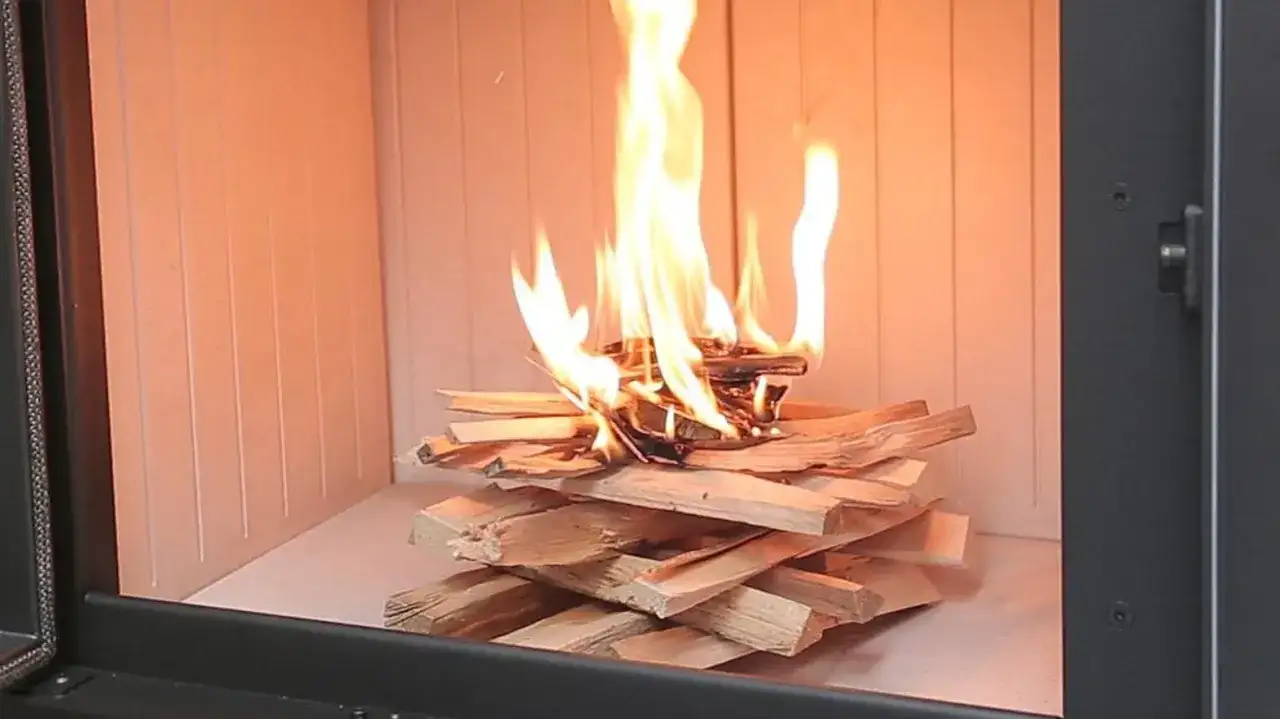 Ogień płonie na ułożonych szczapach drewna. Dowiedz się, jak rozpalić w kominku bez podpałki, używając tylko drewna.