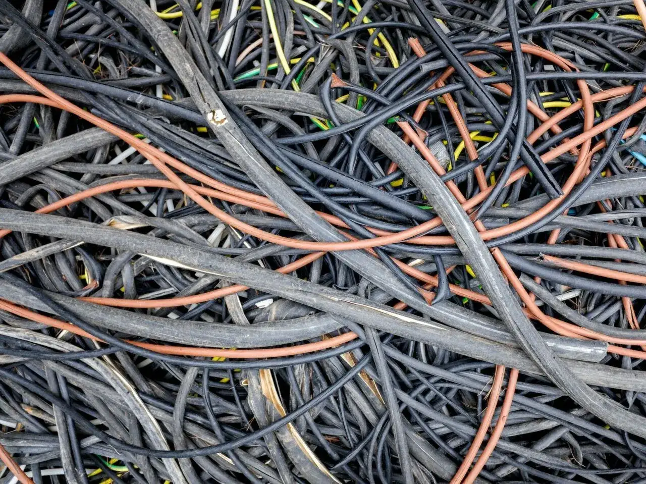 Plątanina kabli, w tym pomarańczowych i czarnych, może być myląca przy wyborze, jaki kabel do licznika 3 fazowego.