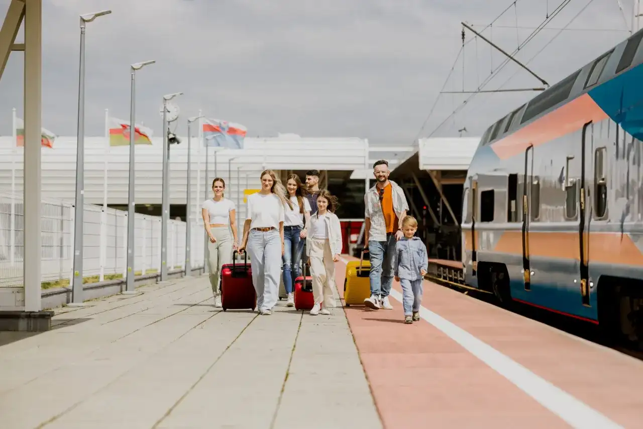 Rodzina z walizkami na peronie, obok pociągu. Planujesz podróż? Sprawdź, jak dojechać do Lublina!