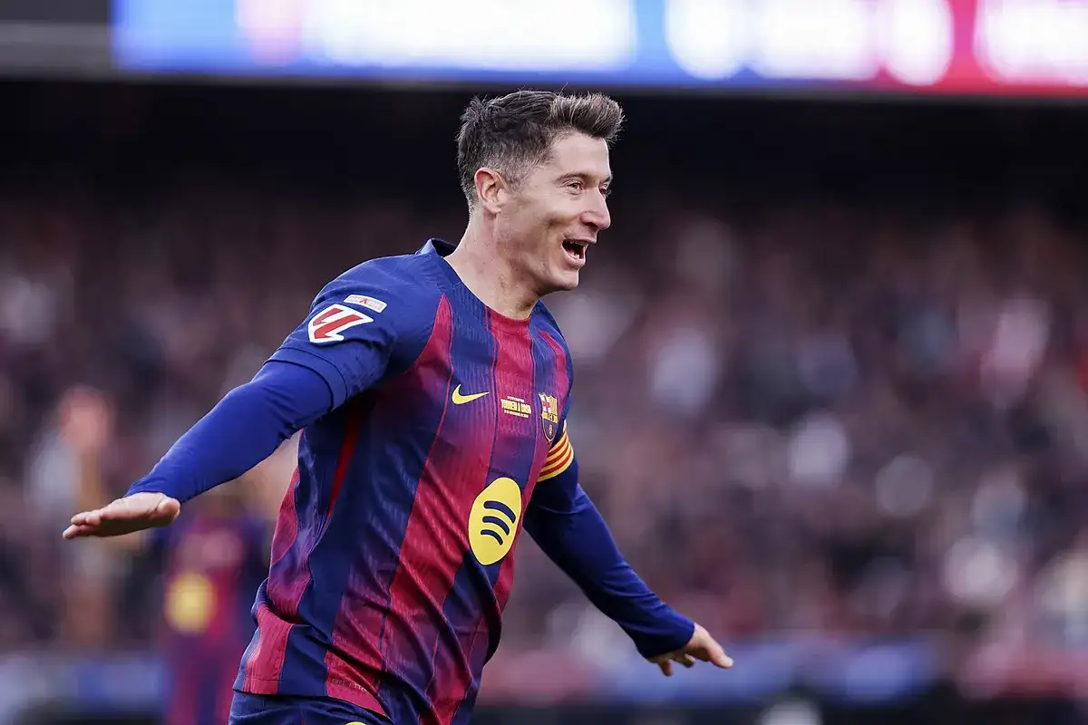 Piłkarz Robert Lewandowski w koszulce FC Barcelony świętuje bramkę na tle trybun.