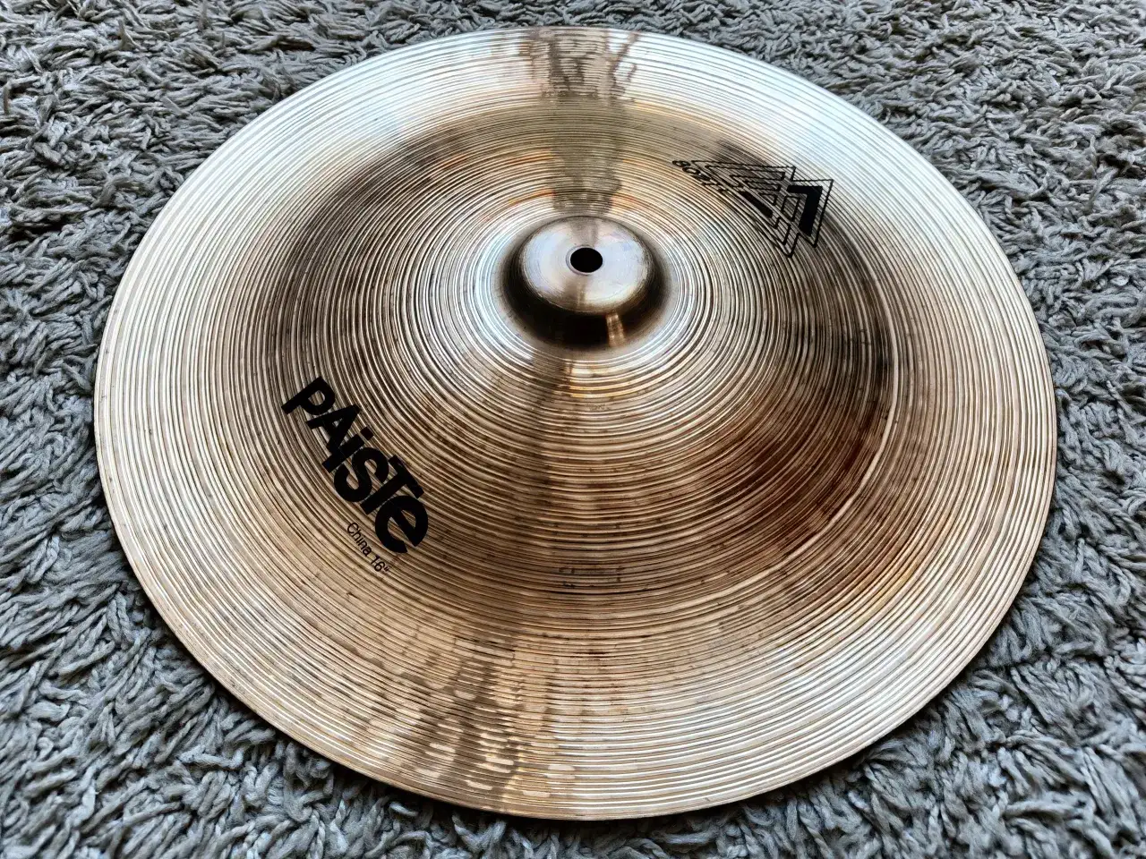 Paiste China 16" - ciche talerze perkusyjne, gotowe do tworzenia unikalnych brzmień na tle szarego dywanu.
