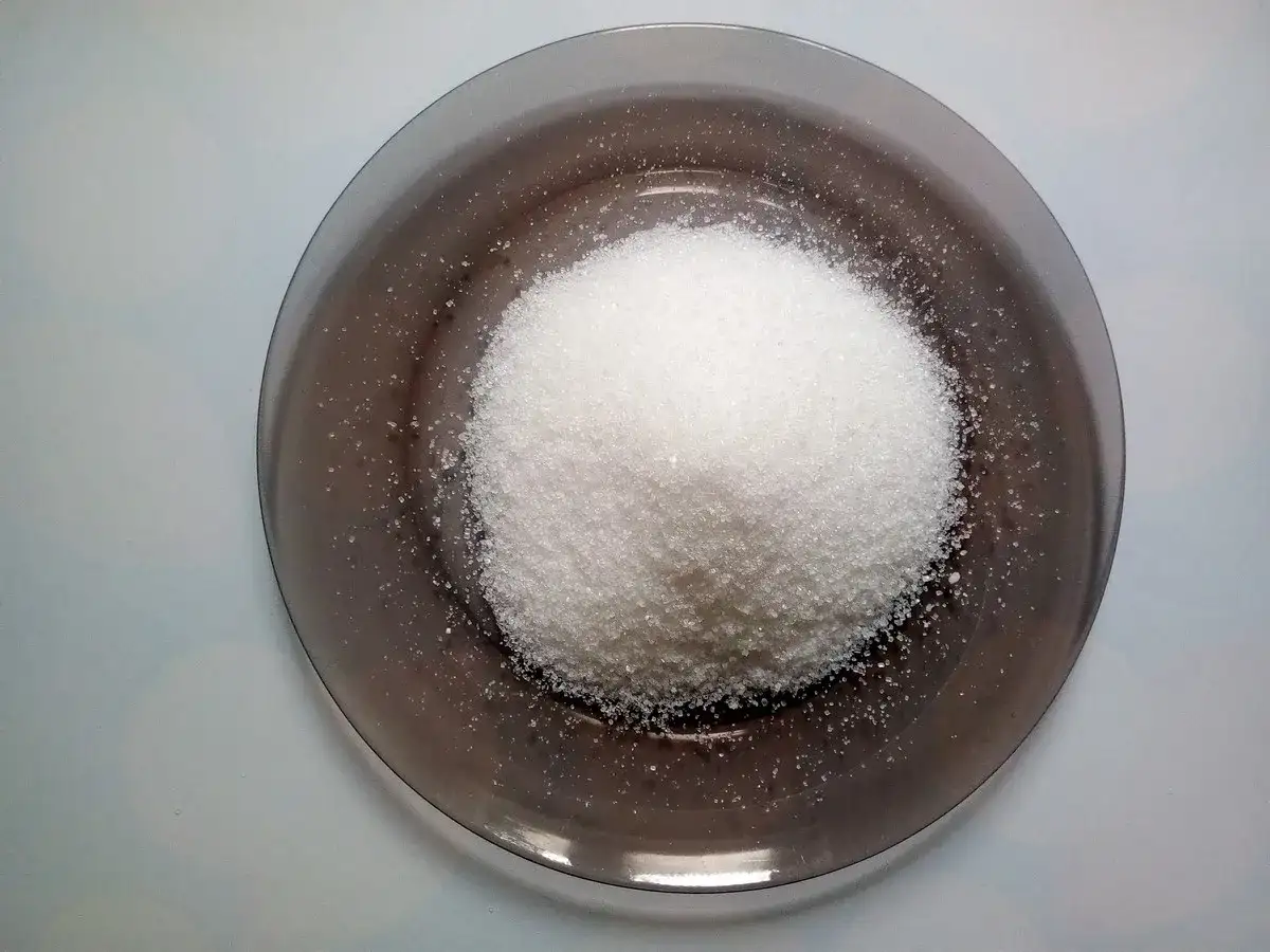 Kopka białego cukru na ciemnym talerzu.