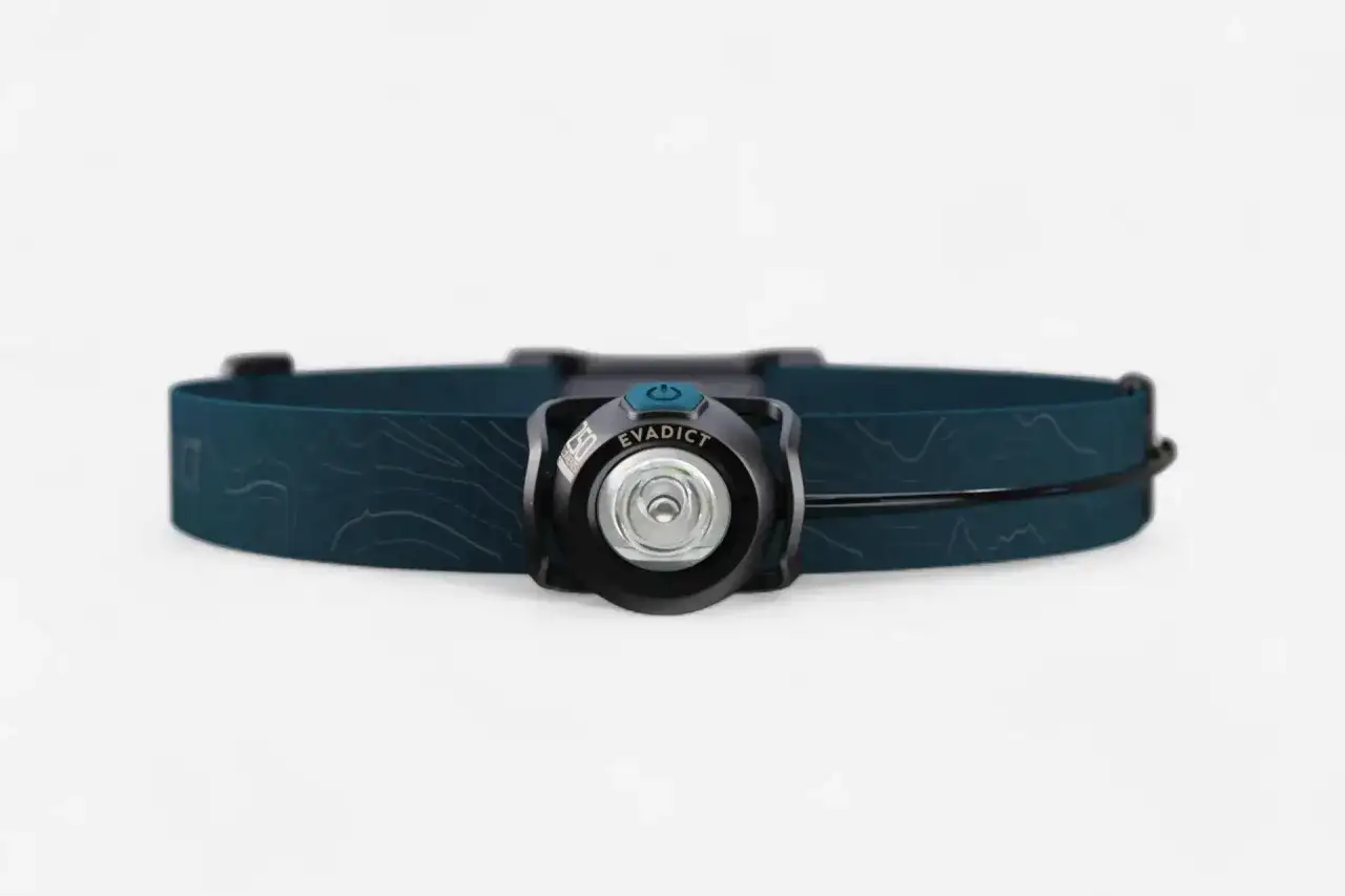 Czołówka do biegania Evadict z niebieską opaską i wzorem mapy. Idealna na nocne treningi.