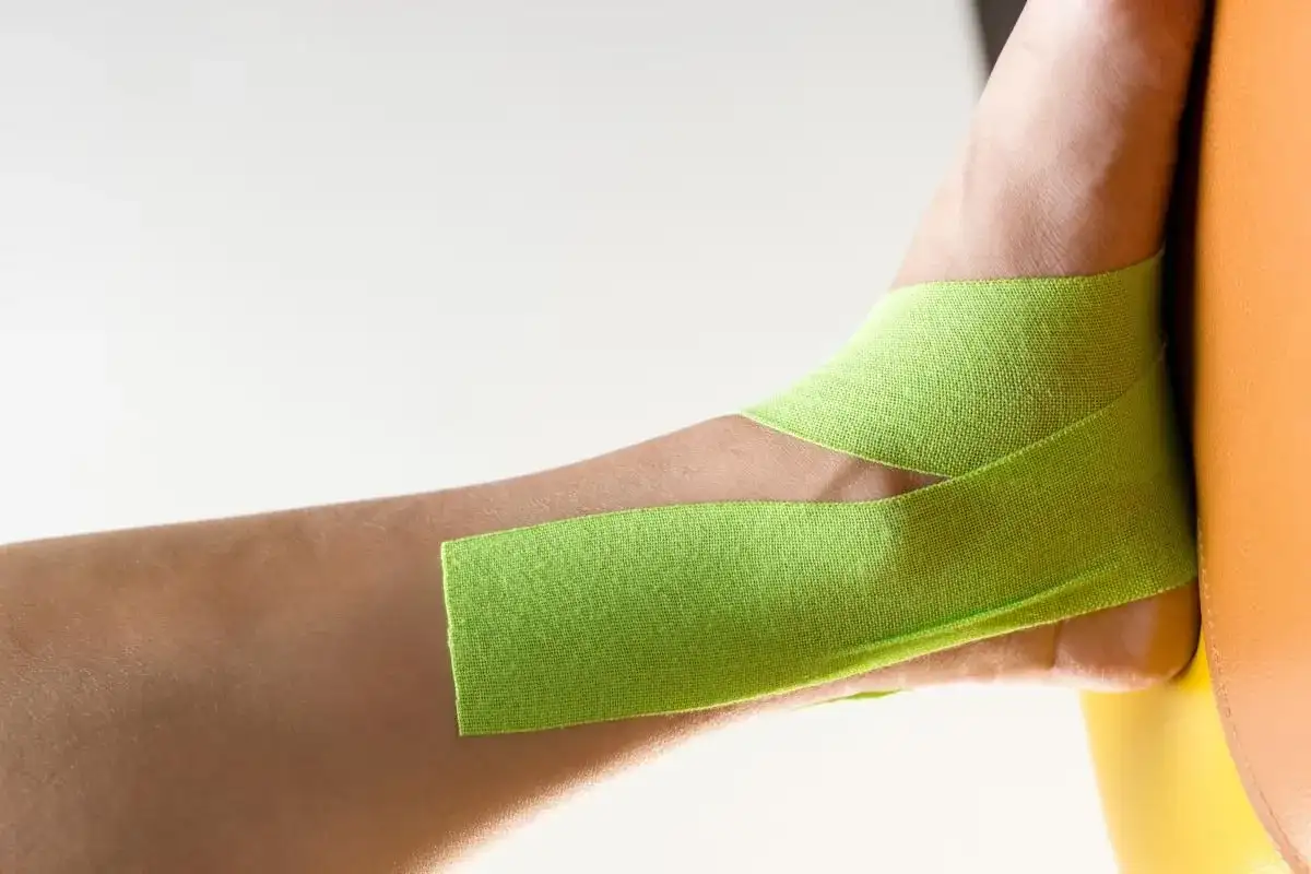 Taping na stopę koślawą u dziecka, zielona taśma kinezjotapingowa stabilizuje staw skokowy.