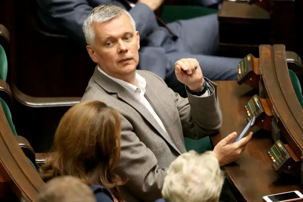 Tomasz Siemoniak, polityk o polskim pochodzeniu, w parlamencie, z telefonem w dłoni.