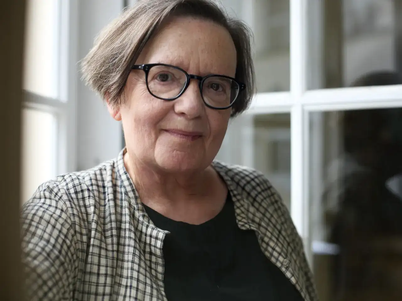 Portret starszej kobiety w okularach, w kratowanej koszuli.