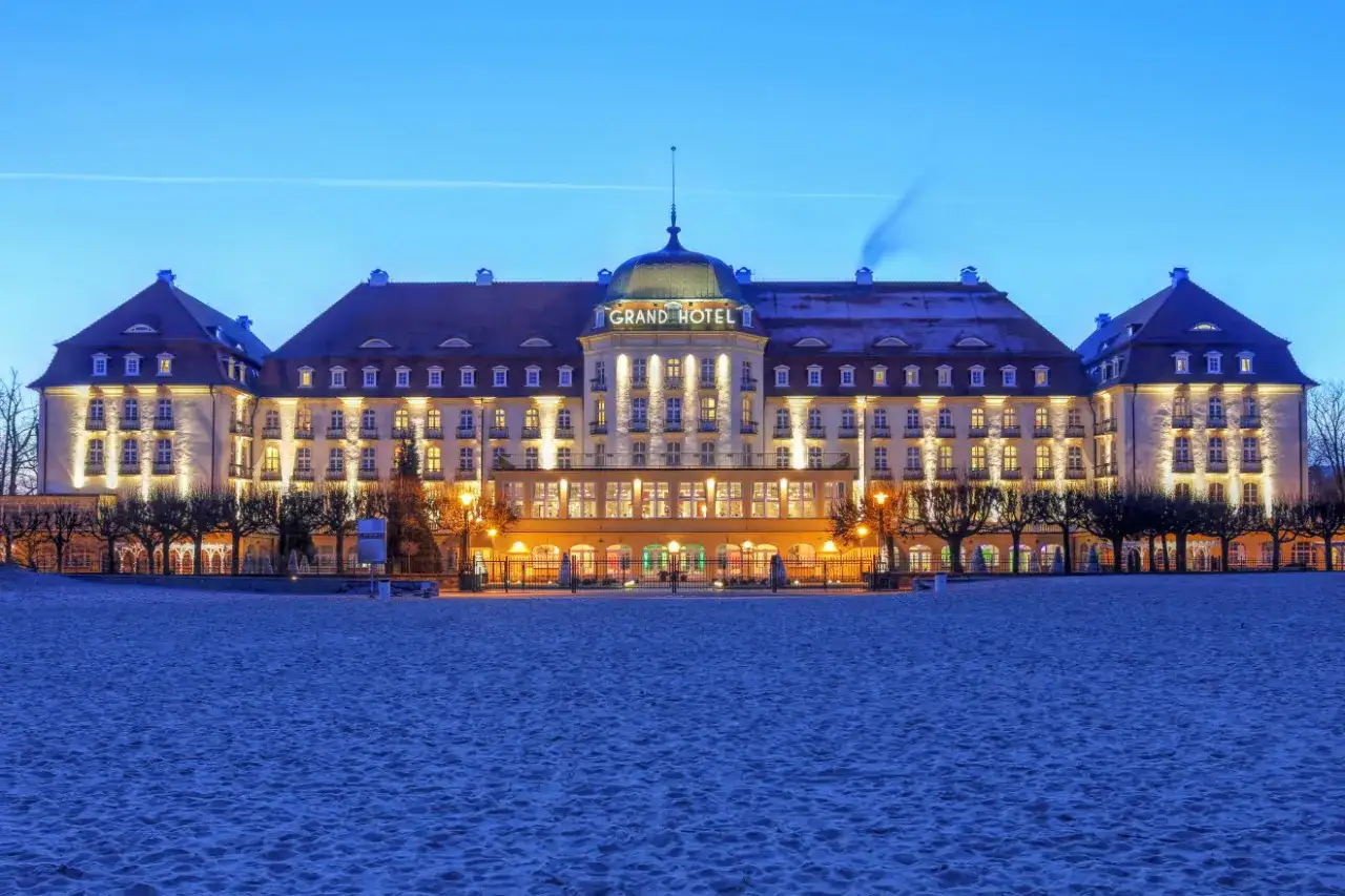 Grand Hotel w Sopocie, jeden z najpiękniejszych hoteli w Polsce, lśni nocą nad piaszczystą plażą.
