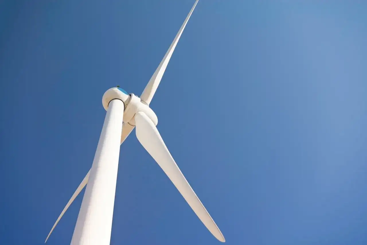 Biała turbina wiatrowa bez pozwolenia na tle błękitnego nieba.