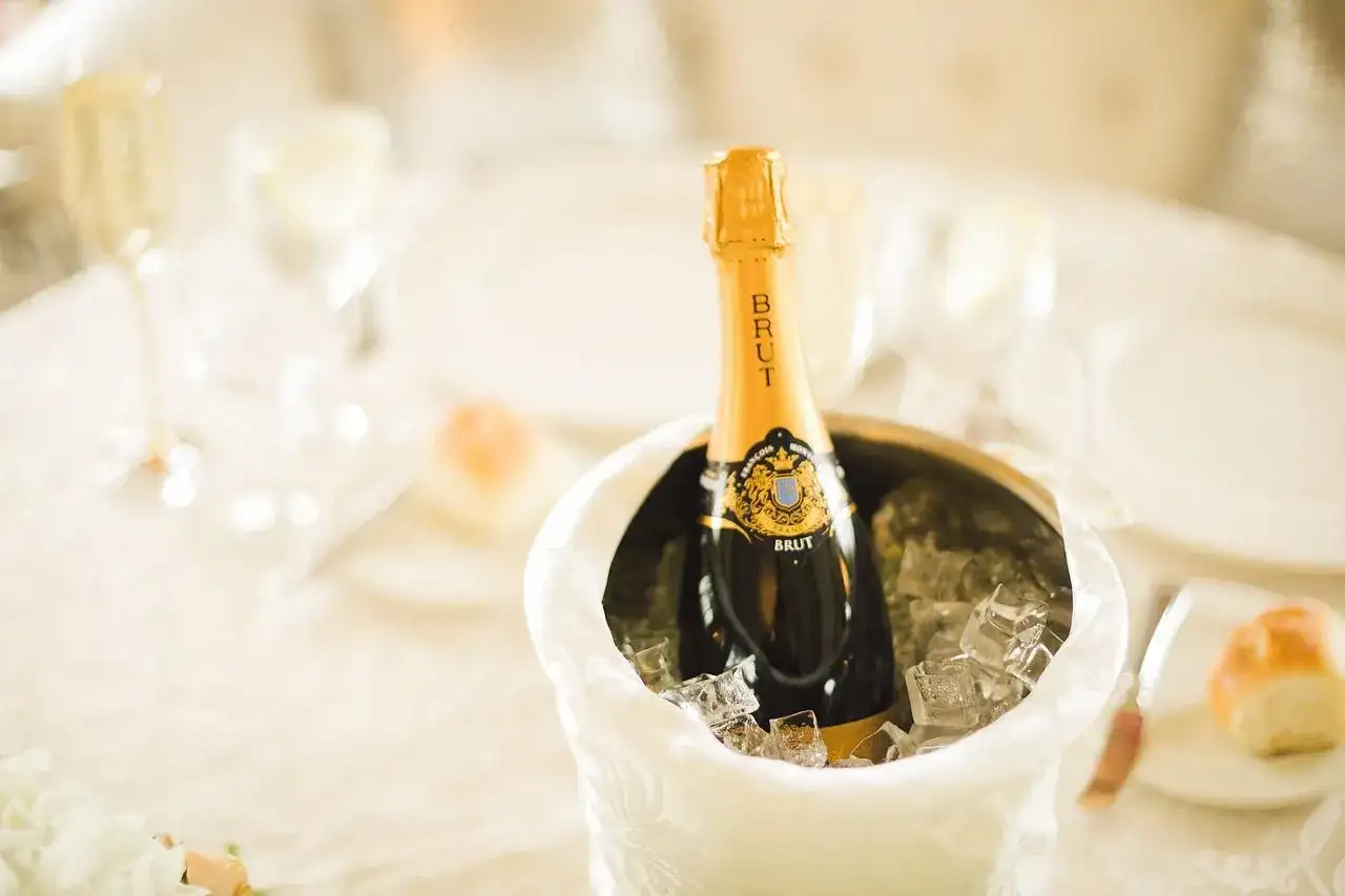 Butelka szampana Brut w wiaderku z lodem na stole weselnym.