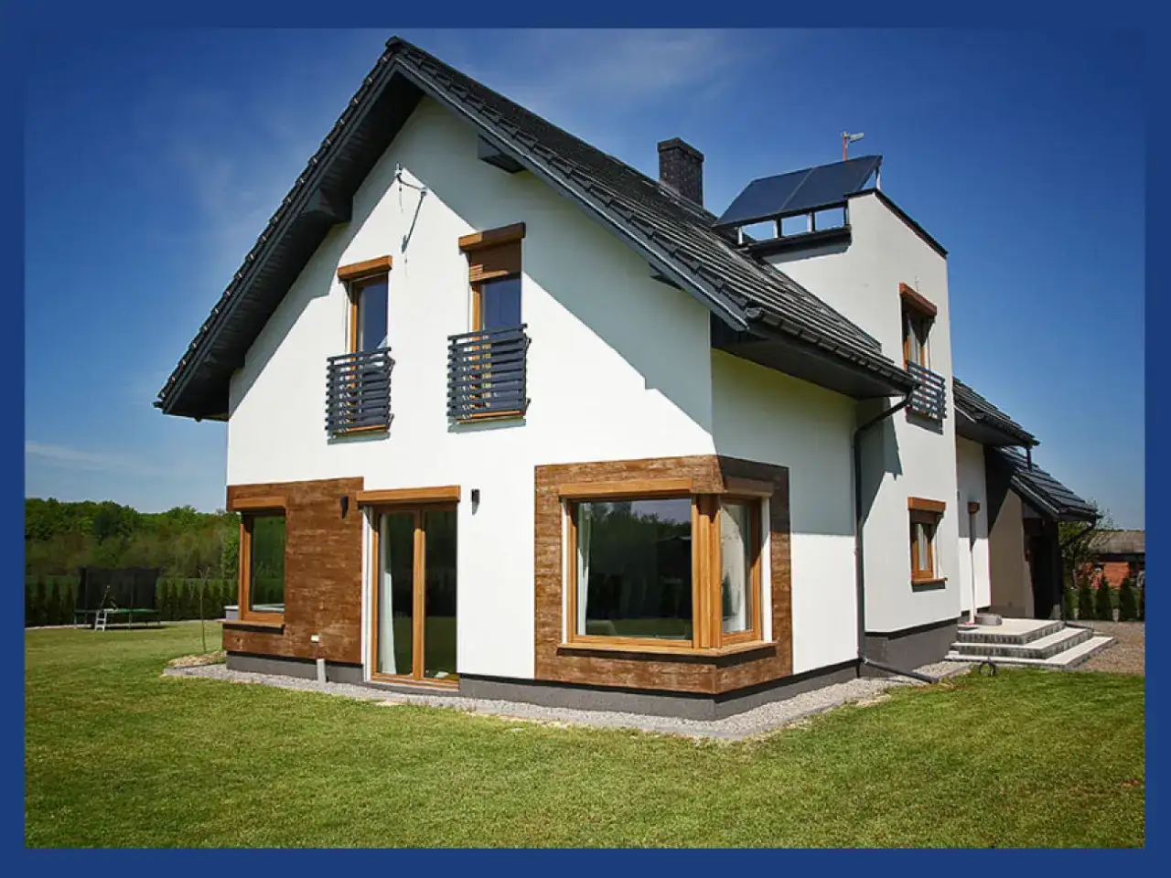 Nowoczesny dom z białym tynkiem, drewnianymi elementami i antracytowym dachem. Okna w kolorze winchester dodają elegancji.