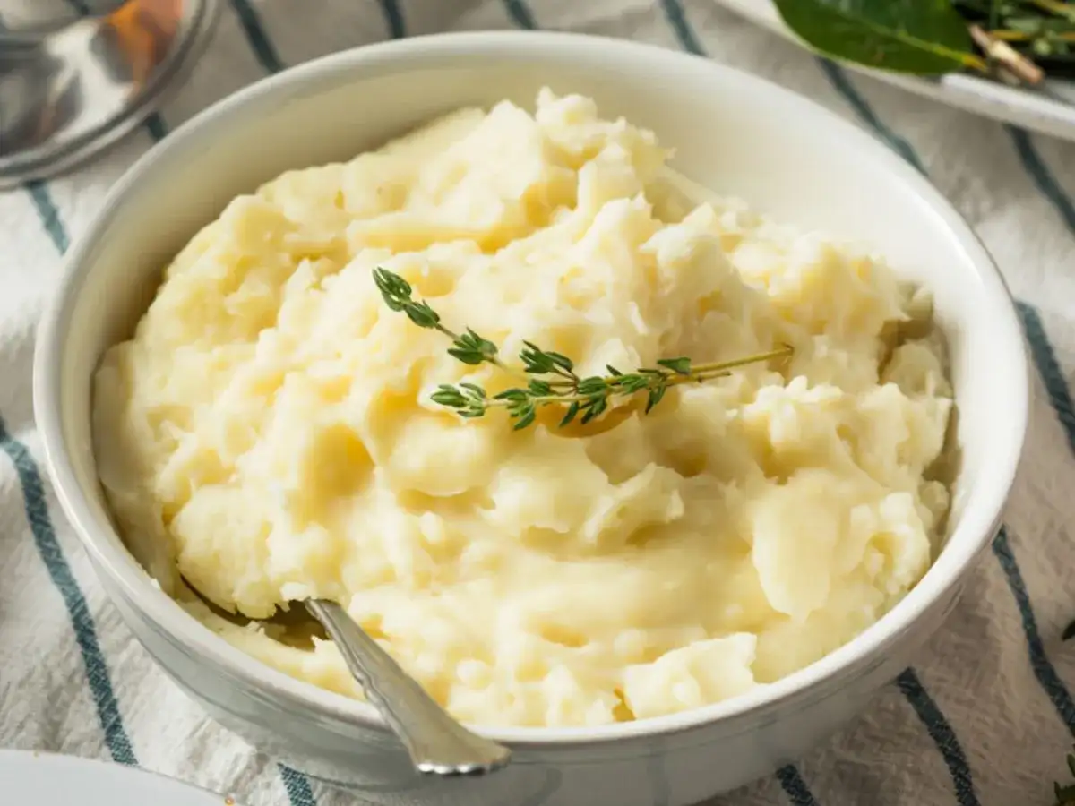 Puszyste puree ziemniaczane bez mleka, udekorowane gałązką tymianku. Idealne dla tych, którzy szukają sposobu, jak zrobić puree ziemniaczane bez mleka.