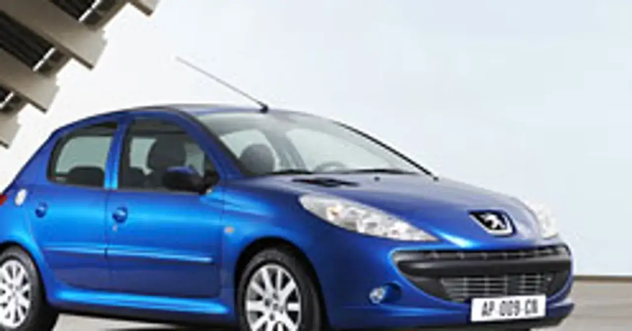 Niebieski Peugeot 206 1.1 stoi na tle nowoczesnej architektury.