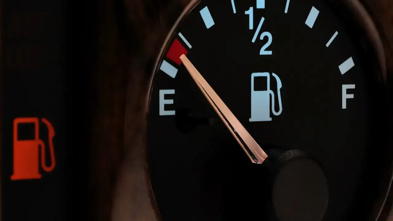 Wskaźnik paliwa w Toyocie Yaris pokazuje niski poziom. Czerwona lampka ostrzegawcza z ikoną dystrybutora paliwa świeci się, a wskazówka na wskaźniku znajduje się blisko litery "E", sygnalizując niski **pojemność baku**.