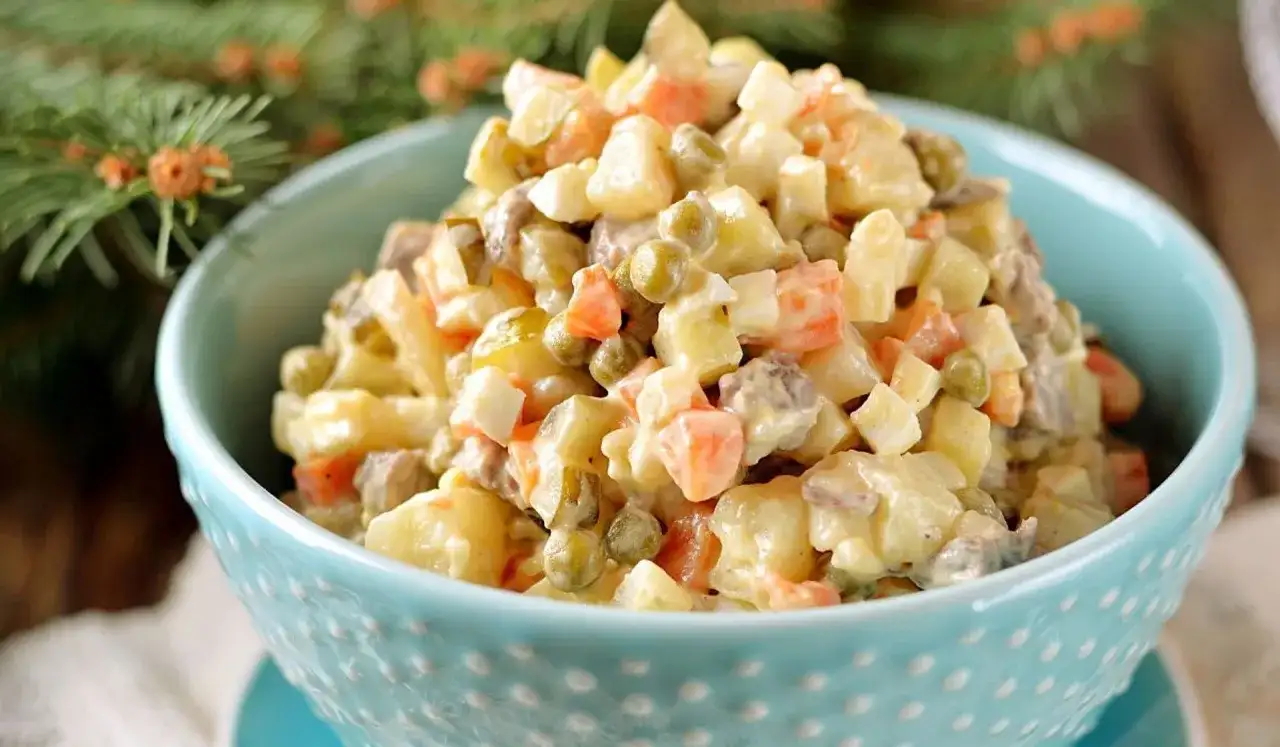 Sałatka jarzynowa w niebieskiej misce, pełna ziemniaków, marchewki, groszku i jajek. Czy do sałatki jarzynowej daje się musztardę? To pytanie zadaje sobie wielu.