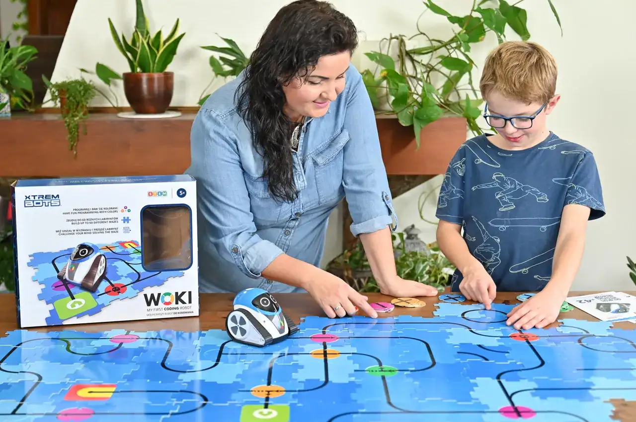 Mama i syn bawią się robotem WOKI, ucząc się kodowania dla 6 latka. Kolorowe klocki tworzą labirynt.