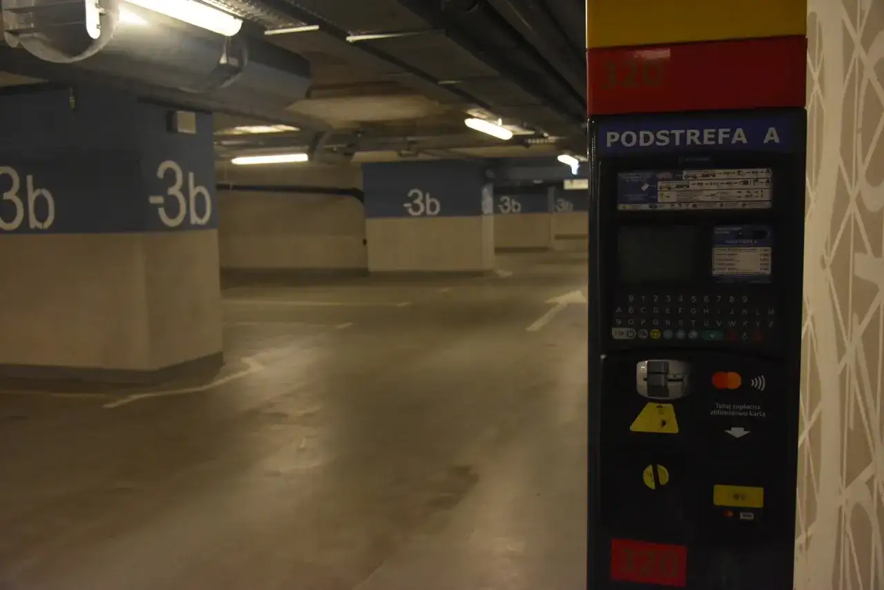 Podziemny parking na dworcu fabrycznym jest płatny. Widać parkingowy automat z klawiaturą i opcjami płatności.