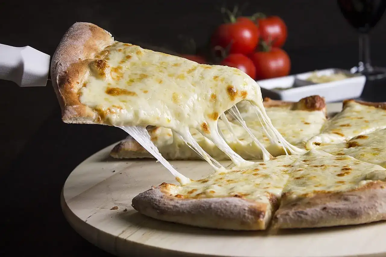 Gorąca pizza z ciągnącym się serem, podana na desce.