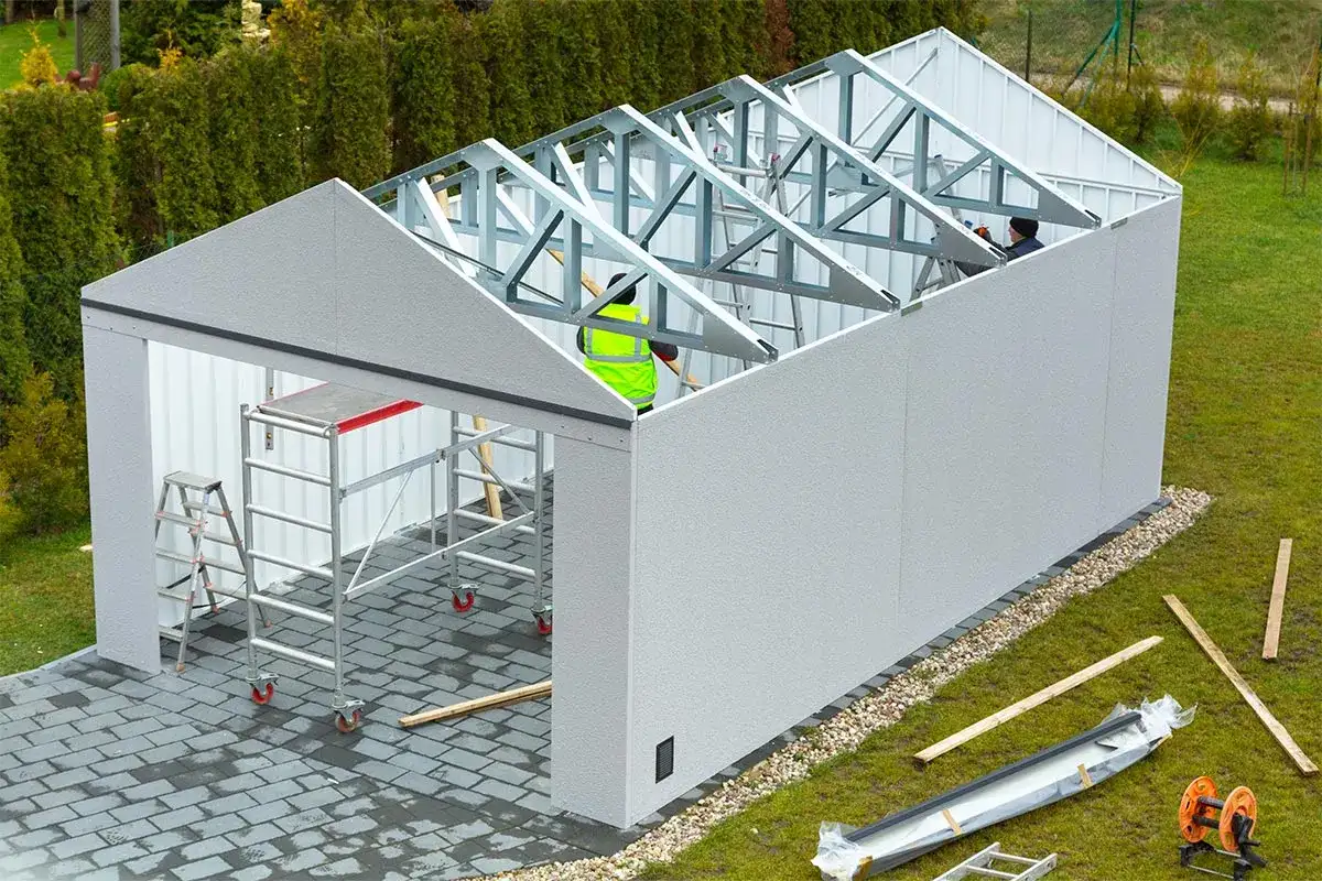 Budowa garażu w toku. Pracownicy montują konstrukcję dachu. Czy na budowę garażu potrzebne jest pozwolenie? To pytanie nurtuje wielu inwestorów.