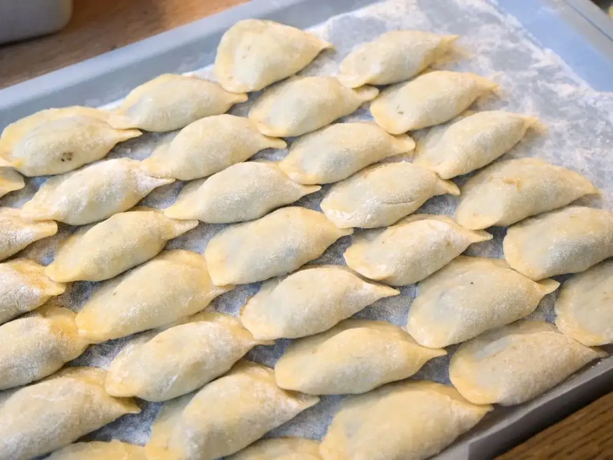 Ułóż surowe pierogi na tacy, posypane mąką, aby wiedzieć, jak przechowywać pierogi.