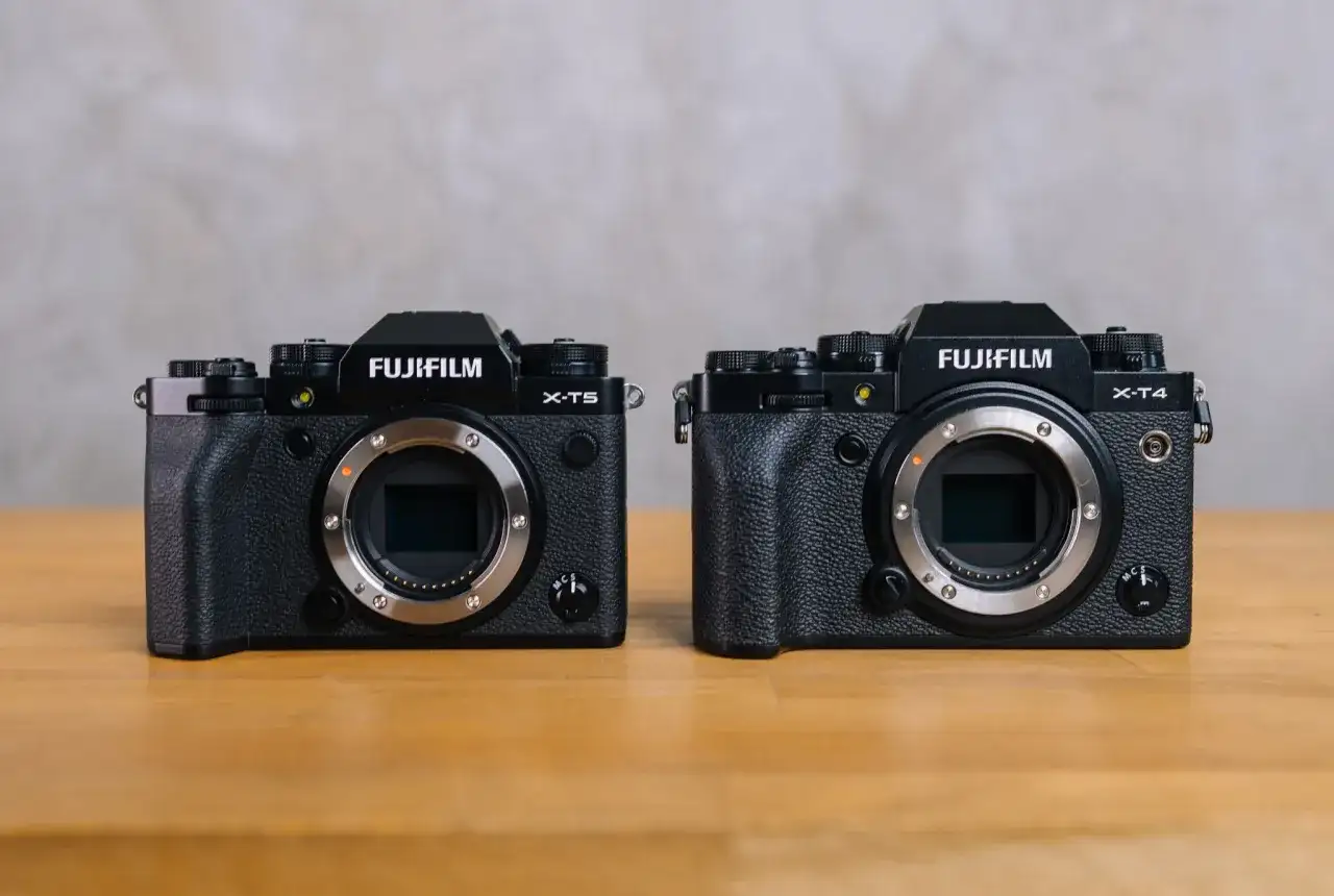 Dwa aparaty Fujifilm: X-T5 i X-T4, stojące obok siebie na drewnianym stole.