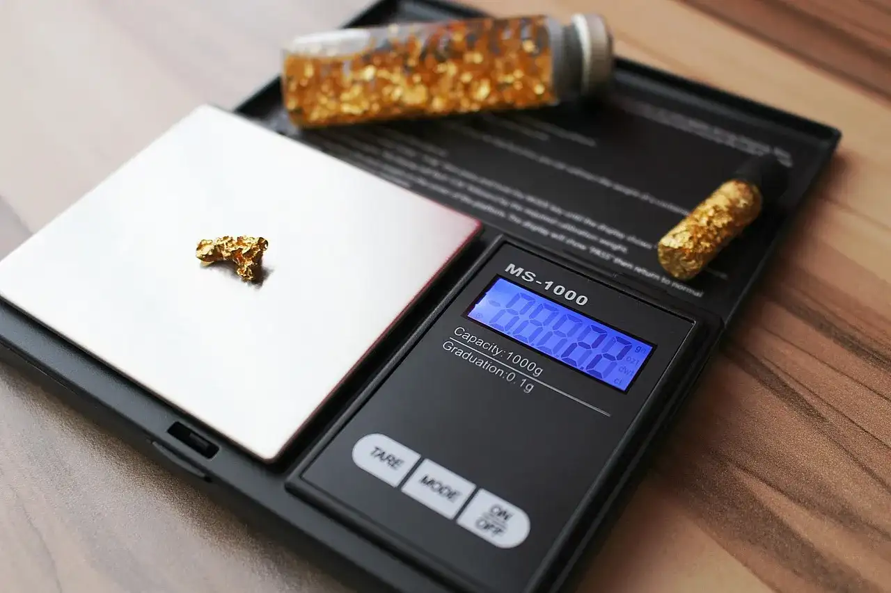 Złote płatki i samorodki na wadze jubilerskiej.