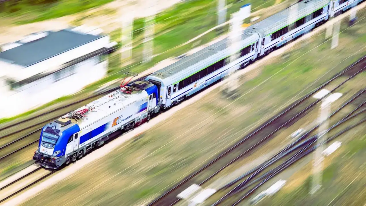 Pociąg Intercity pędzi po torach, oferując szybki sposób, jak dojechać z Krakowa do Dąbek nad morzem.