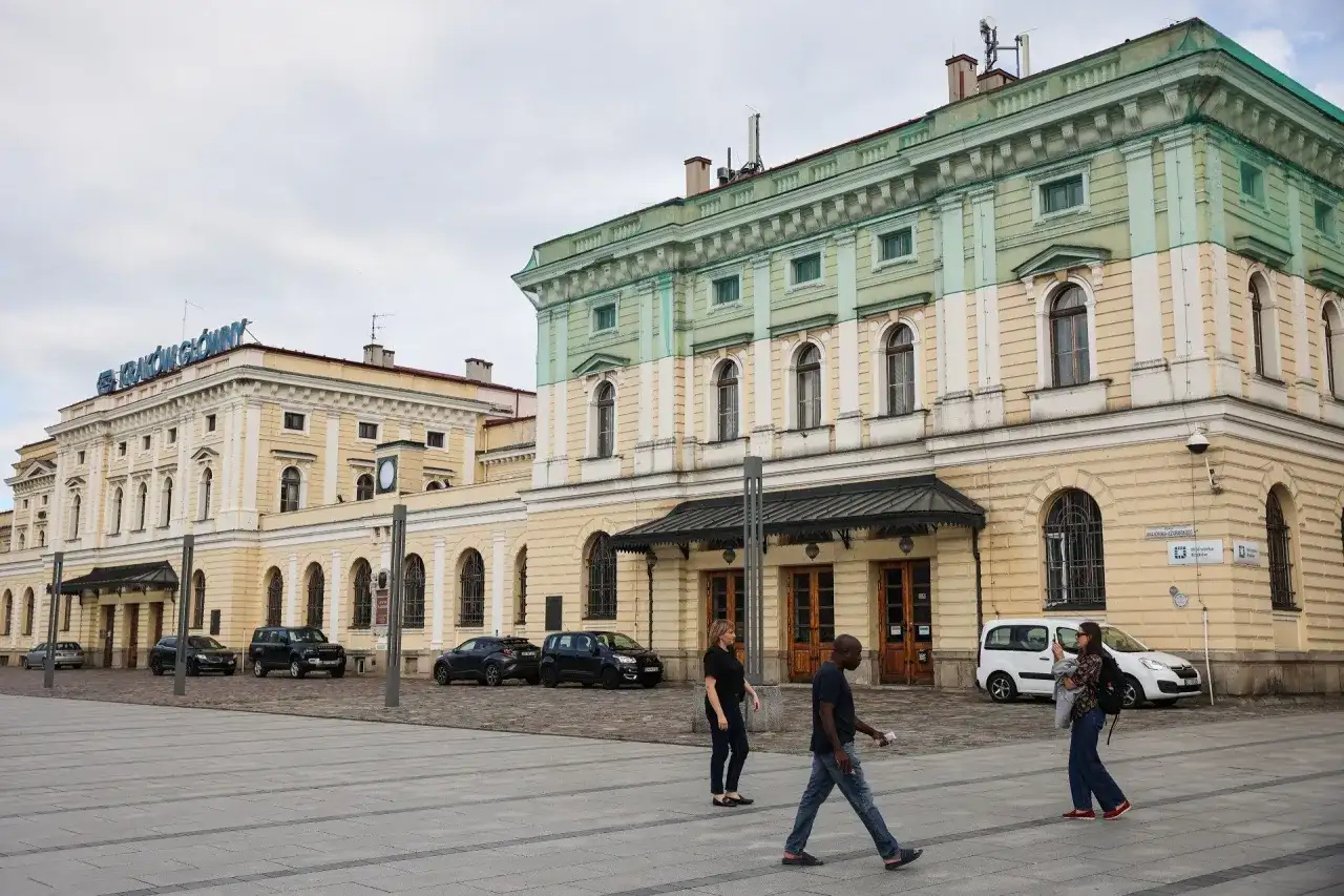 Kraków Główny. Krótki spacer z dworca na rynek, przez plac przed zabytkowym budynkiem, gdzie przechodzą ludzie.