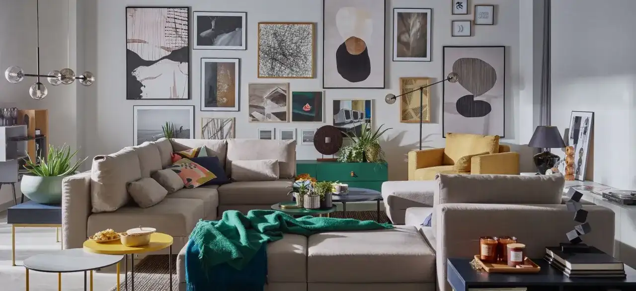 Nowoczesny salon z wygodną kanapą i bogatą ścianą ze zdjęciami. W tle zielona komoda i żółte fotele.