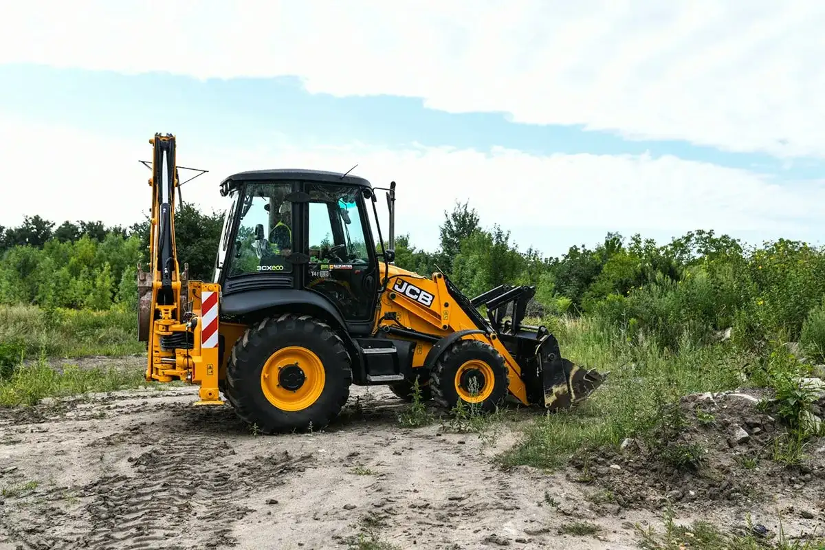 Żółta koparko-ładowarka JCB na placu budowy. Uprawnienia na koparko ładowarkę do czego uprawniają? Do obsługi maszyn budowlanych, takich jak ta.