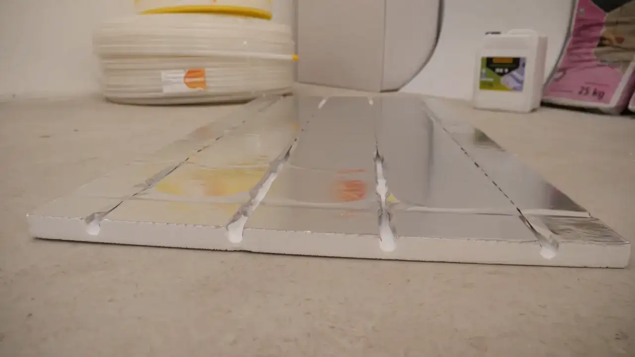 System ogrzewania podłogowego bez wylewki z folią aluminiową i wyżłobieniami na rury.