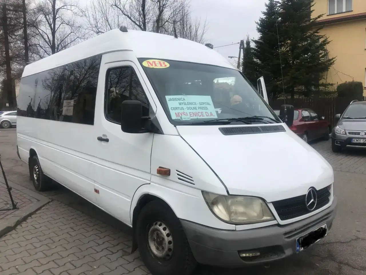 Biały bus z napisem "Jasienica, Myślenice - Szpital, Certus - Dolne Przed, Myślenice D.A." stoi na ulicy.