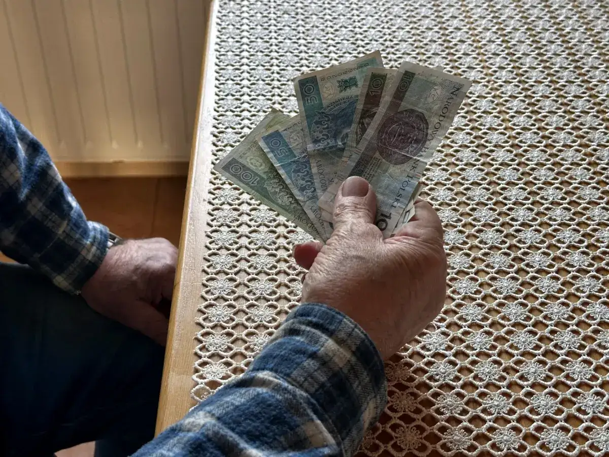 Dłoń trzyma polskie banknoty. Czy to odpowiedź na pytanie, ile zarabia opiekun wytchnieniowy?