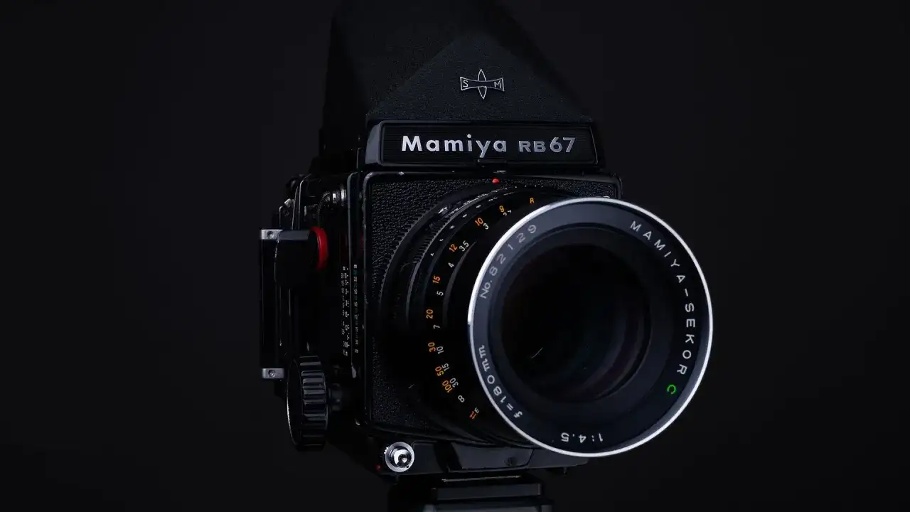 Czarny aparat Mamiya RB67 z obiektywem Mamiya-Sekor C f=180mm. Idealny do zdjęć, które wymagają precyzji i jakości, jaka klisza do aparatu jest w stanie zapewnić.