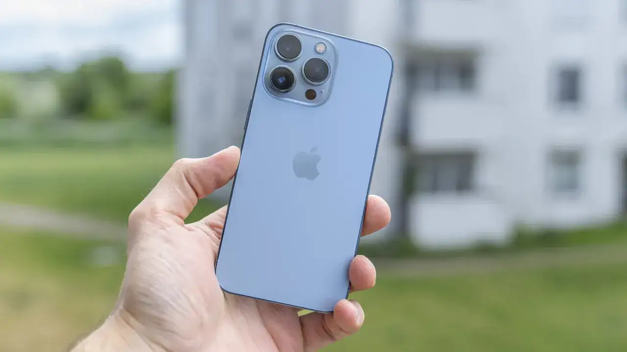 Niebieski iPhone 13 Pro z potrójnym aparatem w dłoni, gotowy do uchwycenia pięknych chwil.
