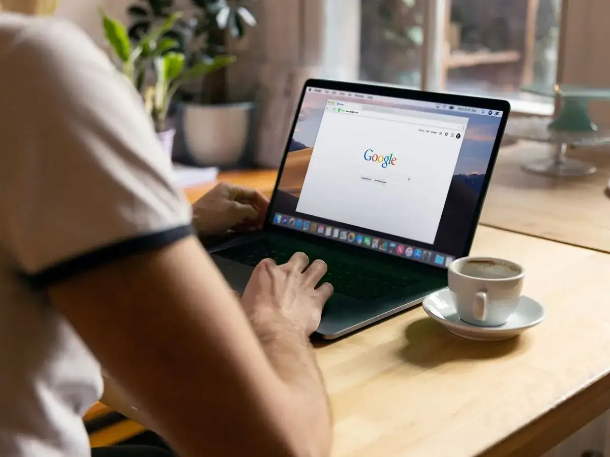 Osoba przy kawie uczy się, jak zmniejszyć stronę w przeglądarce na laptopie.