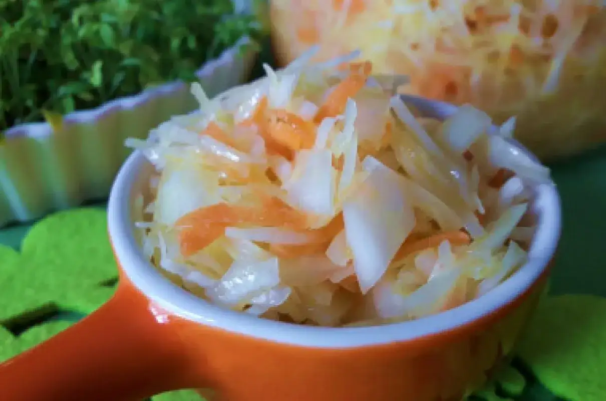 Surówka z białej kapusty i marchewki w pomarańczowej miseczce.