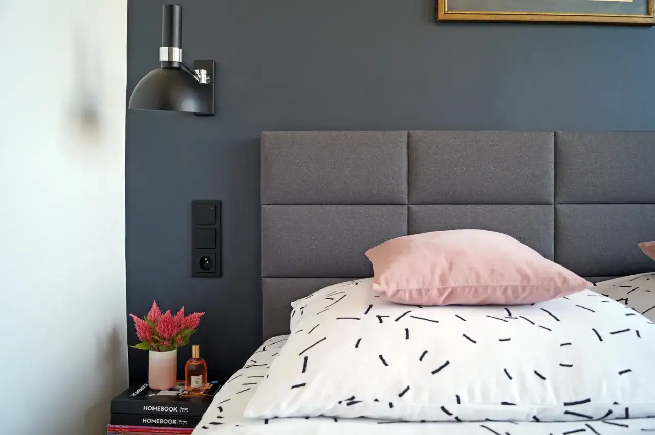 Czarny włącznik światła przy łóżku znajduje się na wygodnej wysokości, tuż obok gniazdka.