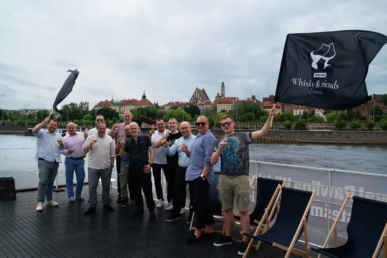 Grupa mężczyzn świętuje na statku, unosząc kieliszki. Czy warto inwestować w whisky kolekcjonerską? Portfel inwestycyjny 2026.