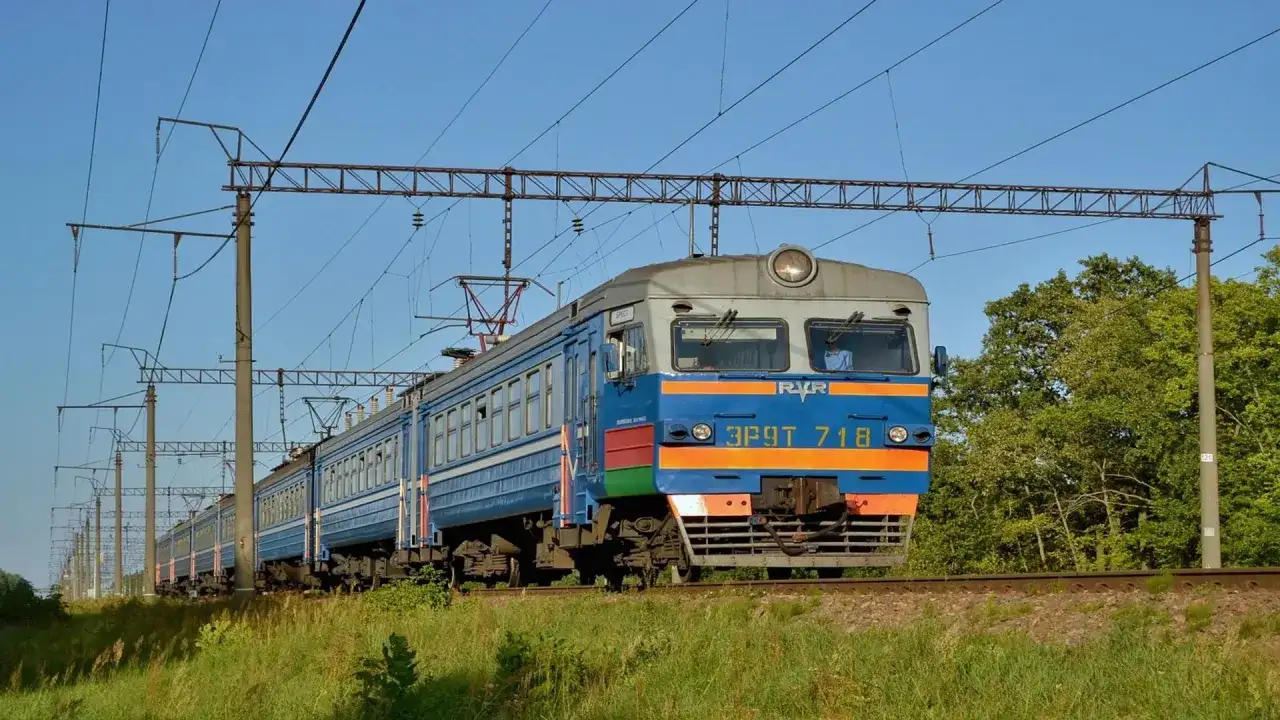 Pociąg elektryczny jedzie po torach, a nad nim widać sieć trakcyjną. To idealny sposób, jak dojechać pociągiem do Kamienia Pomorskiego.