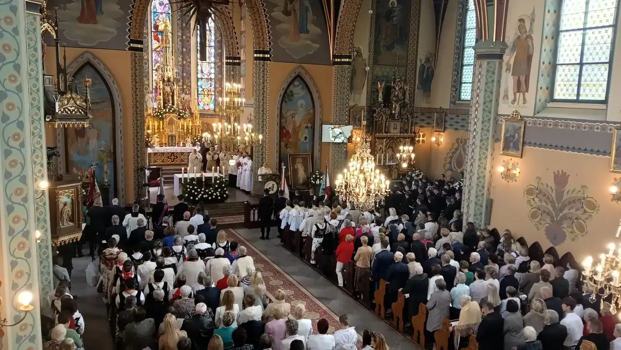 Uroczystość w kościele z wiernymi i duchownymi przy ołtarzu.