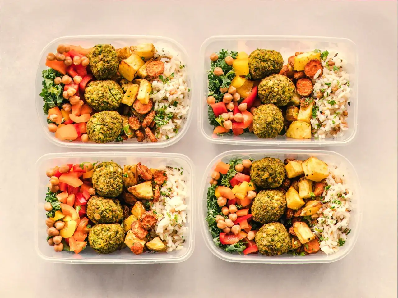 Cztery pojemniki z posiłkami: falafel, ryż, pieczone warzywa i sałatka. Idealny jadłospis na dietę dobrych produktów.