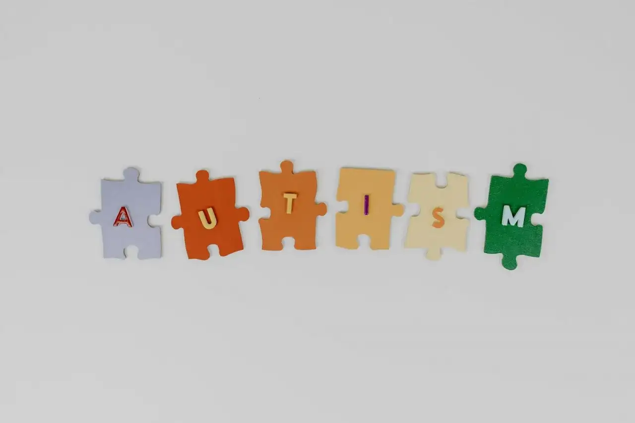 Kolorowe puzzle układają się w napis AUTISM. Każdy element symbolizuje inny stopień niepełnosprawności w spektrum autyzmu.