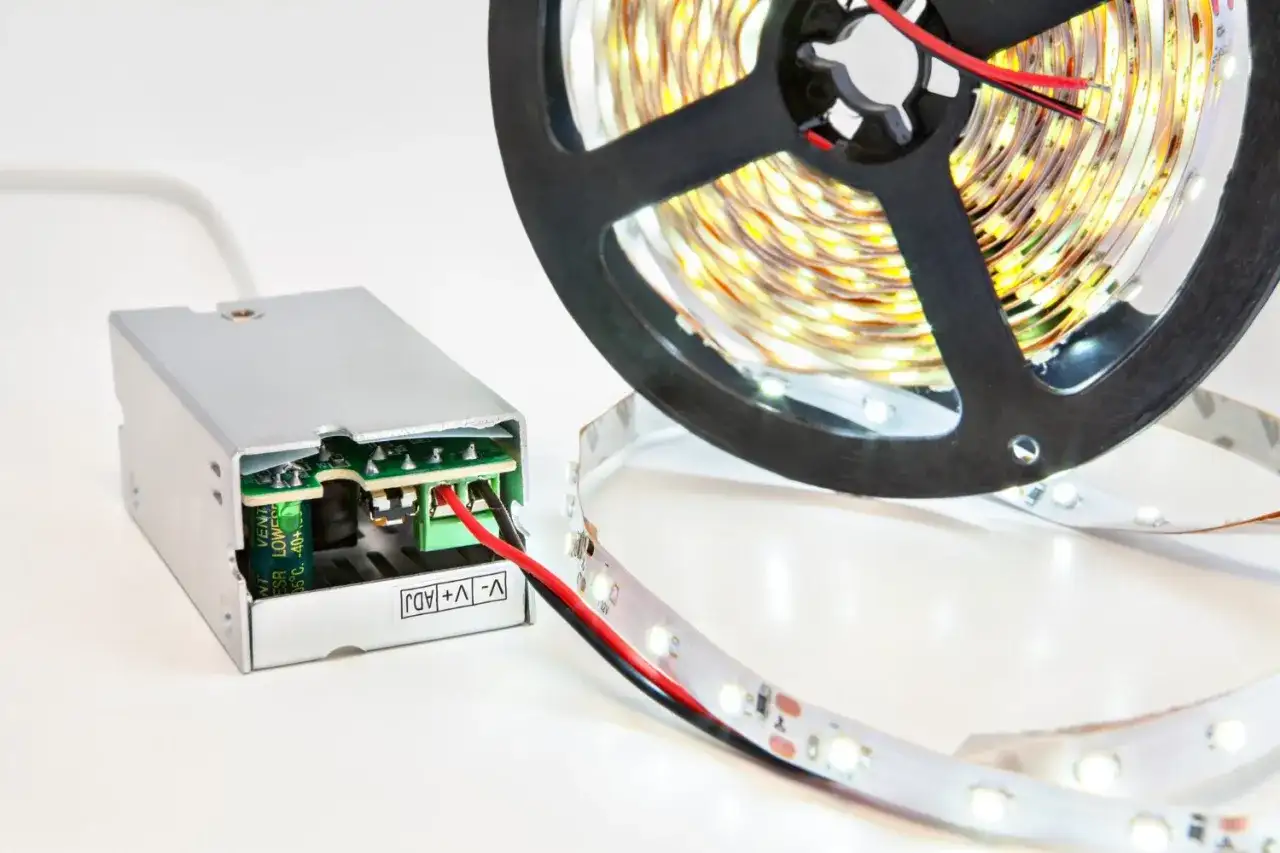 Zasilacz i rolka taśmy LED z widocznymi przewodami. Dowiedz się, jak połączyć taśmę LED, by stworzyć własne oświetlenie.